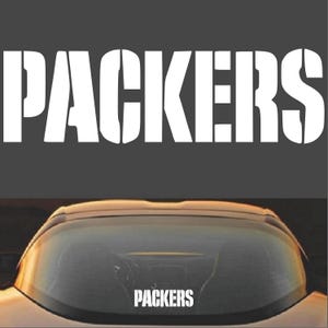 Puede incluir: Un coche blanco con una pegatina en la luneta trasera que dice "PACKERS".