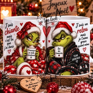 Op de afbeelding: Twee witte keramische mokken met groene, Grinch-achtige figuren in kerstmutsen. De linker mok toont een vrouwelijk personage met Franse tekst, de rechter mok een mannelijk personage met Franse tekst en rode hartjes als decoratie.