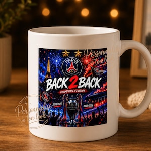 Peut inclure: Un mug en céramique blanc avec une impression graphique du logo du Paris Saint-Germain, la tour Eiffel, des feux d'artifice et un trophée. Le texte indique BACK 2 BACK, CHAMPIONS D'EUROPE, 2024/2025 et 2025/2026. Le design inclut deux étoiles dorées.
