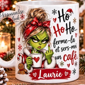 Può includere: Una tazza in ceramica bianca con un personaggio verde con chignon e fiocco rosso, che tiene una tazza di caffè mentre mostra il dito medio. Il testo recita Ho Ho Ho... ferme-la et sers-moi un café. Il nome Laurie è stampato su un banner rosso.