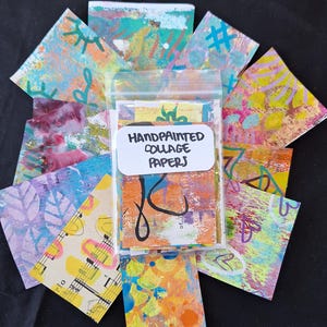 May include: A clear plastic bag filled with colorful hand-painted collage papers. The bag has a label that reads "Handpainted Collage Papers".