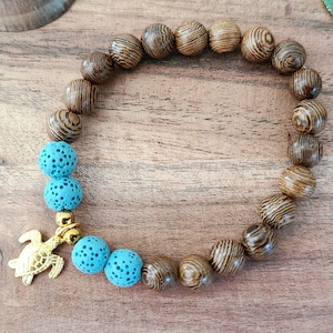 May include: A wooden beaded bracelet with a turquoise lava stone charm and a gold turtle pendant.