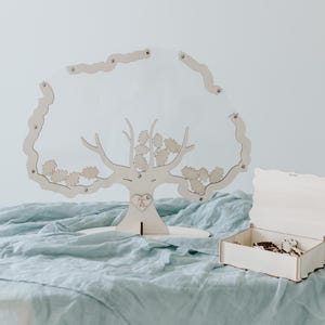 Könnte beinhalten: Ein hölzerner, baumförmiger Gästebuch für Hochzeiten mit einem Herz an der Basis und einer kleinen Holzkiste mit gewelltem Rand. Der Baum ist mit kleinen Holzblättern verziert und die Kiste ist offen mit kleinen Holzh Herzen im Inneren.