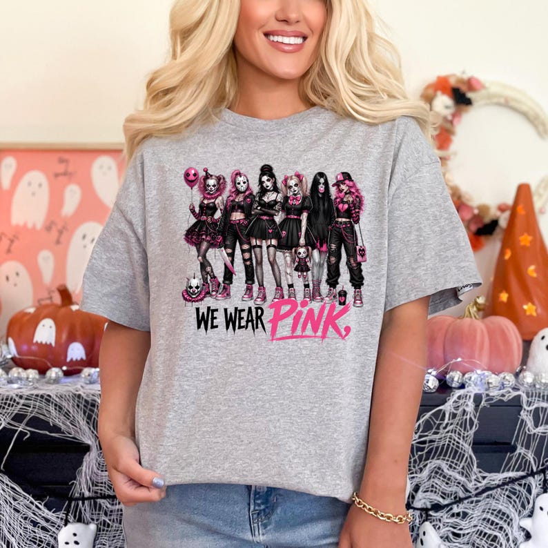 A woman wearing a gray t-shirt with a graphic design of a group of women in black and pink outfits, along with the text "WE WEAR PINK."