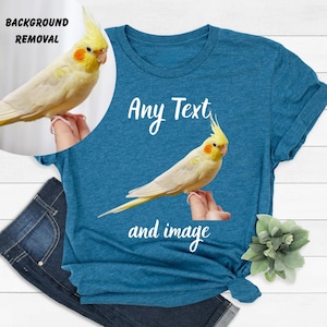 a blue t-shirt with a yellow bird perched on it, along with a pair of jeans and a small green plant.