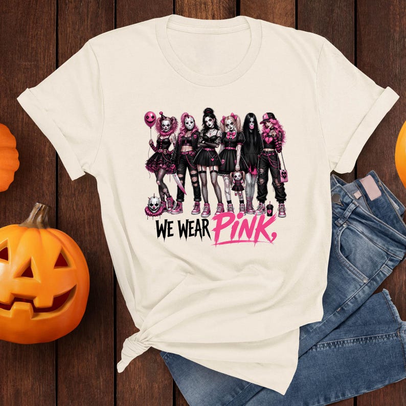 A white t-shirt with a graphic design featuring a group of women dressed in dark clothing and accessories, along with the text "WE WEAR PINK."