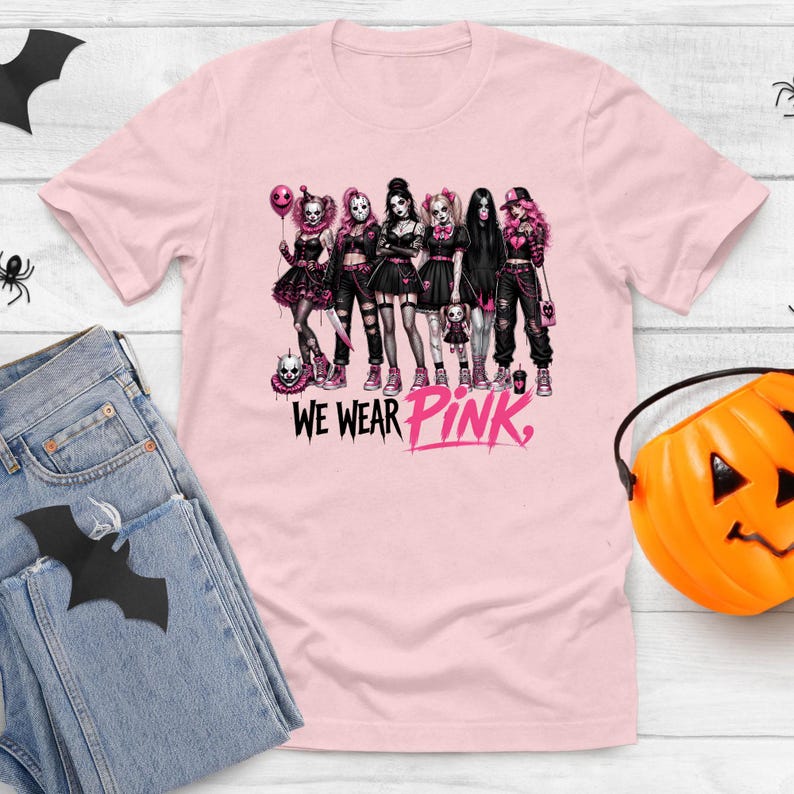 A pink t-shirt with a graphic design of a group of women dressed in dark clothing and accessories, along with the text "WE WEAR PINK."