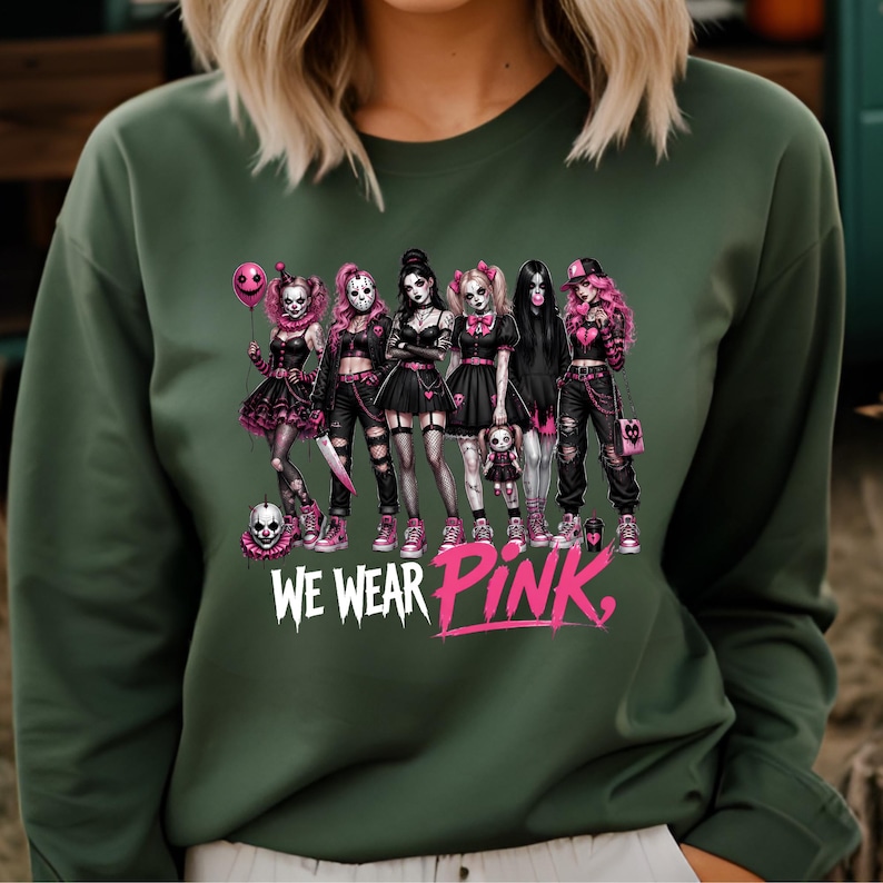 A woman wearing a green sweater with a graphic design featuring a group of women with various styles and accessories, including skull-like elements.
