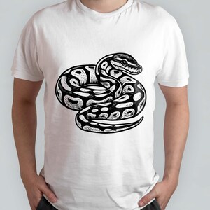 K&ouml;nnte beinhalten: Wei&szlig;es T-Shirt mit einer schwarz-wei&szlig;en Illustration einer Schlange in einer eingerollten Position. Das Schlangenmuster hat ein Muster aus Punkten und Linien mit detailliertem Kopf und Schuppen. Das T-Shirt ist ein Freizeitartikel.
