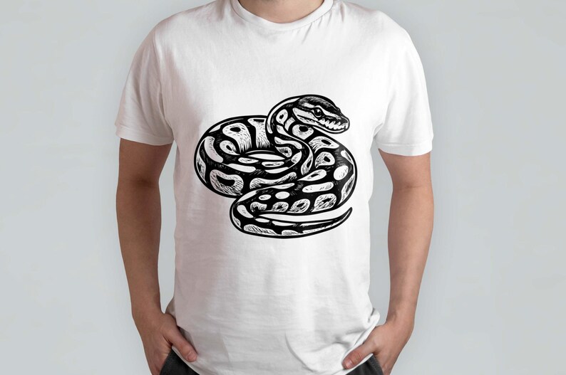 K&ouml;nnte beinhalten: Wei&szlig;es T-Shirt mit einer schwarz-wei&szlig;en Illustration einer Schlange in einer eingerollten Position. Das Schlangenmuster hat ein Muster aus Punkten und Linien mit detailliertem Kopf und Schuppen. Das T-Shirt ist ein Freizeitartikel.