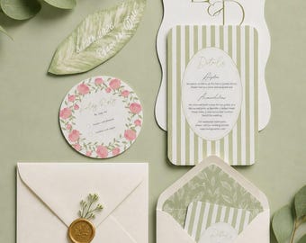 May include: A wedding stationery set featuring a leaf-shaped Save the Date, a circular RSVP card with pink floral accents, and a rectangular details card with green stripes. Includes two cream envelopes, one sealed with a gold wax seal.