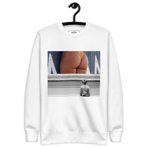 May include: White sweatshirt featuring a black and white image. The image shows a person's rear in orange underwear, viewed through a fence, and a child looking at it. The sweatshirt has a tag that says "Styles 90".