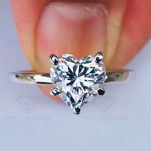 May include: A silver ring with a heart-shaped diamond. The diamond is clear and sparkly.