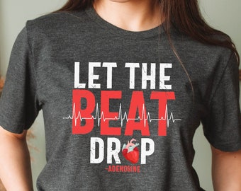 Könnte beinhalten: Ein dunkelgraues T-Shirt mit dem Text "Let the beat drop - Adenosine" in Weiß und Rot. Ein rotes Herz mit einer weißen EKG-Linie ist im Text enthalten.
