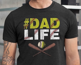 May include: A dark gray t-shirt with the text "#DADLIFE" in white letters with a softball graphic and crossed baseball bats.