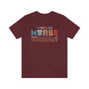 May include: A maroon t-shirt with a vintage-style graphic that says "VINTAGE NURSE (noun) Knows more than she says and notices more than you realize."