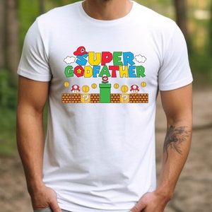 Puede incluir: Camiseta blanca con un gr&aacute;fico colorido de un personaje de videojuego y el texto "SUPER GODFATHER".