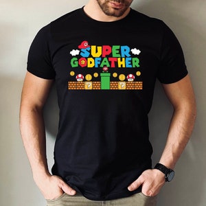 Puede incluir: Camiseta negra con un gr&aacute;fico de un personaje de videojuego y el texto "SUPER GODFATHER".