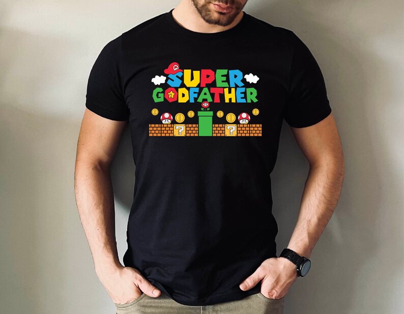 Puede incluir: Camiseta negra con un gr&aacute;fico de un personaje de videojuego y el texto "SUPER GODFATHER".