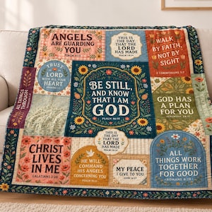 May include: A multi-paneled throw blanket featuring various floral patterns and religious text, including the central phrase Be Still, and Know That I Am God, surrounded by verses like Walk by Faith, Not by Sight and Christ Lives in Me.