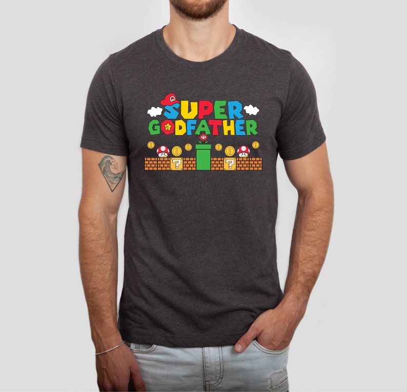 Puede incluir: Una camiseta gris oscuro jaspeada con un gr&aacute;fico de un personaje de Super Mario y el texto "SUPER GODFATHER".