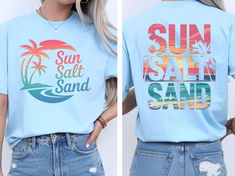 K&ouml;nnte beinhalten: Hellblaues T-Shirt mit tropischem Design. Auf der Vorderseite befinden sich eine Palme und die Worte "Sun Salt Sand" in bunten Farben. Auf der R&uuml;ckseite des Shirts wiederholen sich die Worte "Sun Salt Sand" mit einem Sonnenuntergang und einer Palme.