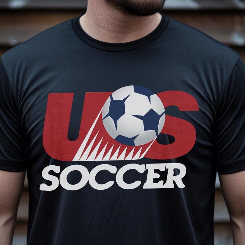 May include: A black short-sleeved t-shirt featuring a graphic design on the chest. The design includes the red text US with white motion lines, a white and navy blue soccer ball, and the word SOCCER printed in white capital letters below.