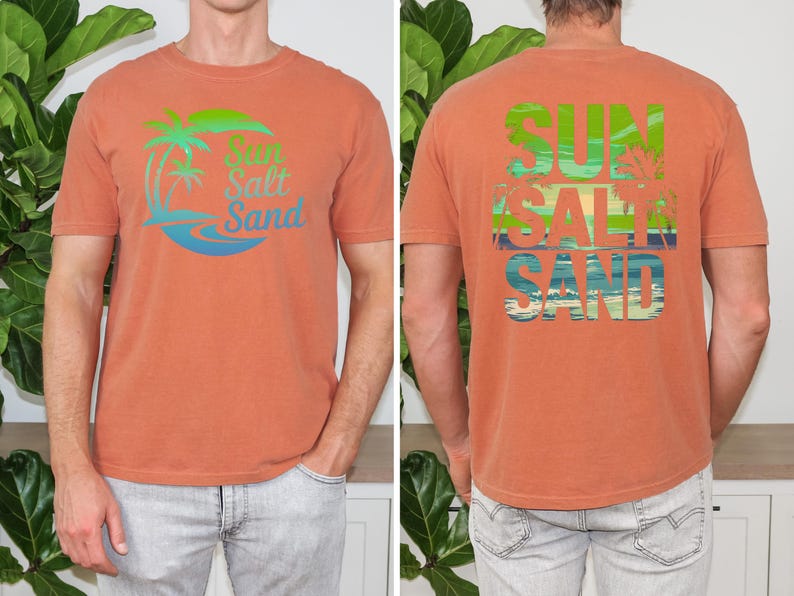 K&ouml;nnte beinhalten: Gebrannt orangefarbenes T-Shirt mit dem Schriftzug "Sun Salt Sand" in einem tropischen Design auf Vorder- und R&uuml;ckseite. Das Design umfasst Palmen und Meereswellen in Gr&uuml;n, Blau und Wei&szlig;.