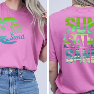 K&ouml;nnte beinhalten: Ein pinkfarbenes T-Shirt mit tropischem Design. Auf der Vorderseite stehen die Worte "Sun Salt Sand" in Gr&uuml;n-, Blau- und Gelbt&ouml;nen mit Palmen und Wellen. Auf der R&uuml;ckseite des Shirts wird der Text in &auml;hnlicher Weise wiederholt.