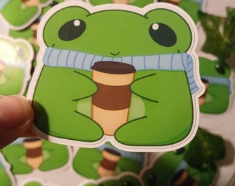 Rana acogedora con café y bufanda (pegatina brillante)