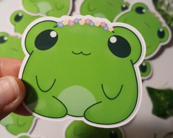 Pegatina brillante de rana con corona de flores de primavera