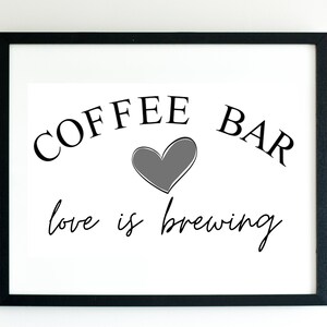 Può includere: Stampa incorniciata in bianco e nero con il testo "COFFEE BAR love is brewing" e un cuore grigio al centro.