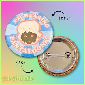 May include: A circular badge featuring a cartoon character illustration. The badge has a blue and white striped background with the words "I'M WEARING PANTALOONS!" in a circular design. The reverse side of the badge is visible, showing a pin.