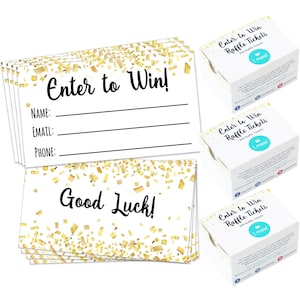 May include: A stack of white raffle tickets with a gold confetti pattern. The tickets have the text "Enter to Win!" and "Good Luck!" printed on them. There are also three boxes of raffle tickets with the text "Enter to Win Raffle Tickets" printed on them.