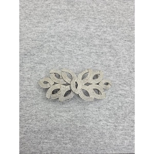 May include: A silver-toned metal belt buckle featuring an intricate, symmetrical openwork design composed of multiple interconnected leaf-like loops with a textured, cross-hatched surface finish throughout the entire decorative piece.
