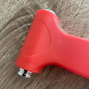 Puede incluir: Un martillo de seguridad rojo con una punta de metal plateada. El martillo est&aacute; dise&ntilde;ado para romper las ventanas de los coches en caso de emergencia.