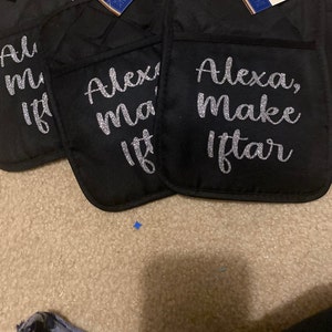 May include: Three black oven mitts with a silver glitter design. The mitts have the text "Alexa, make Iftar" on them.