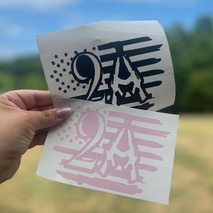 May include: Two vinyl decals featuring the number 24 with an American flag design. One decal is black and white, and the other is pink and white.