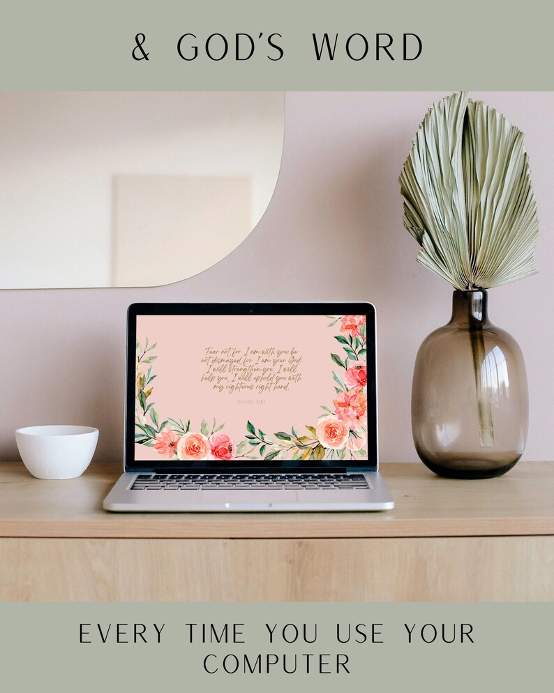 May include: A laptop computer with a pink floral desktop background featuring the text "Fear not, for I am with you; be not dismayed, for I am your God. I will strengthen you; I will help you; I will uphold you with my righteous right hand."  The laptop is on a wooden desk with a white bowl and a vase with a dried palm leaf.