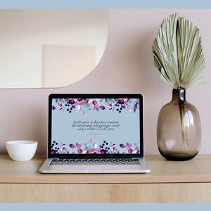 May include: A laptop computer with a floral wallpaper featuring purple and blue flowers. The screen displays a Bible verse: "And the peace of God which surpasses all understanding will guard your hearts and your minds in Christ Jesus." Philippians 4:7