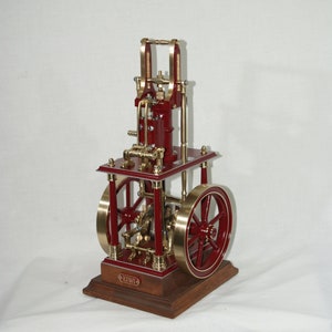 Peut inclure: Modèle de moteur à vapeur détaillé, rouge et or. Il présente deux grands volants, une tuyauterie complexe et une base rectangulaire. La base a un aspect bois. Objet décoratif.