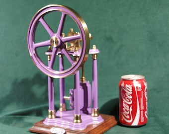 Peut inclure: Un modèle de machine à vapeur en laiton et violet avec un volant d'inertie et une base. Le moteur est à peu près de la taille d'une canette de soda.