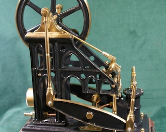 Peut inclure: Une machine à vapeur miniature noire et laiton avec un grand volant d'inertie, des détails complexes et une base en bois.