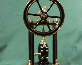 Peut inclure: Un modèle détaillé de machine à vapeur avec un volant noir et doré, soutenu par des colonnes noires et une base en bois. Le modèle présente des accents en laiton complexes et le texte "EIWI" sur la base.