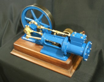 May include: A blue and brass model steam engine with a flywheel, mounted on a wooden base.