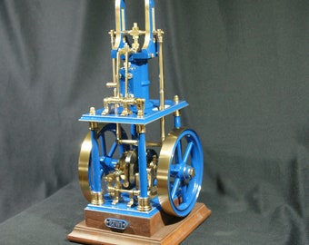 May include: A blue and brass model steam engine with a wooden base. The engine has a flywheel and a piston. The base is labelled "E.W.I."