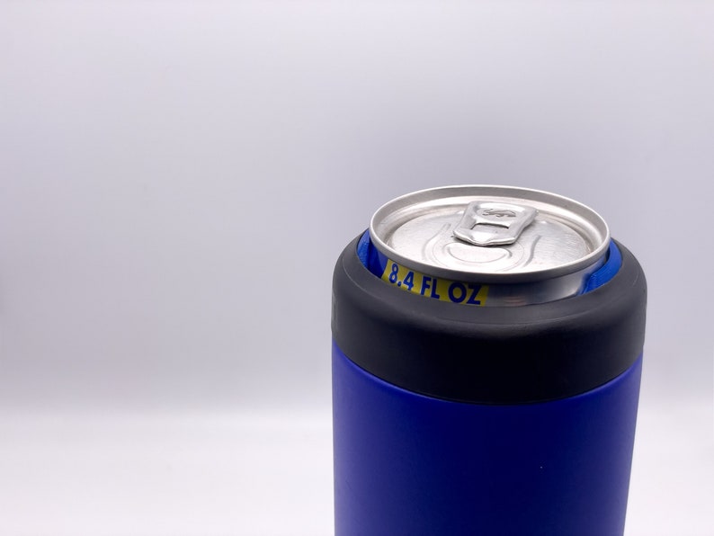 May include: A blue and black insulated can holder with a silver can inside. The can has a yellow label that reads "8.4 FL OZ".