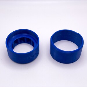 May include: Two blue plastic rings, one with a textured inner surface and the word "Verti" printed on the side.