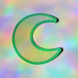 May include: A green crescent moon shaped patch with a white iridescent background. The patch has a textured surface.