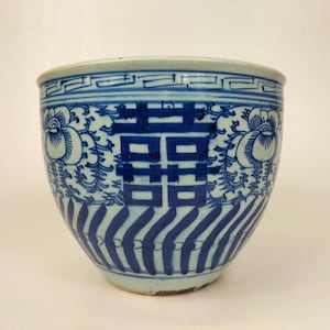 Op de afbeelding: Een blauwe en witte porseleinen kom met een traditioneel Chinees ontwerp. De kom heeft een dubbel gelukssymbool in het midden, omringd door bloemmotieven. De kom is ongeveer 15 cm in diameter.